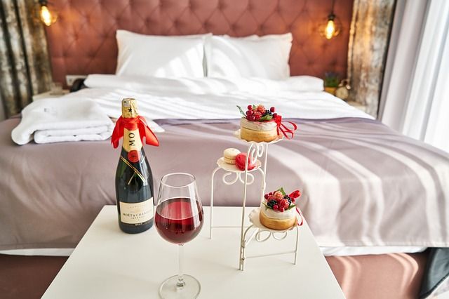 Romantic setting of a bed with wine and deserts sitting in front of it